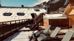 A wooden deck with snow-covered ground and a view of a mountain.