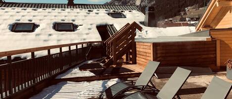 A wooden deck with snow-covered ground and a view of a mountain.