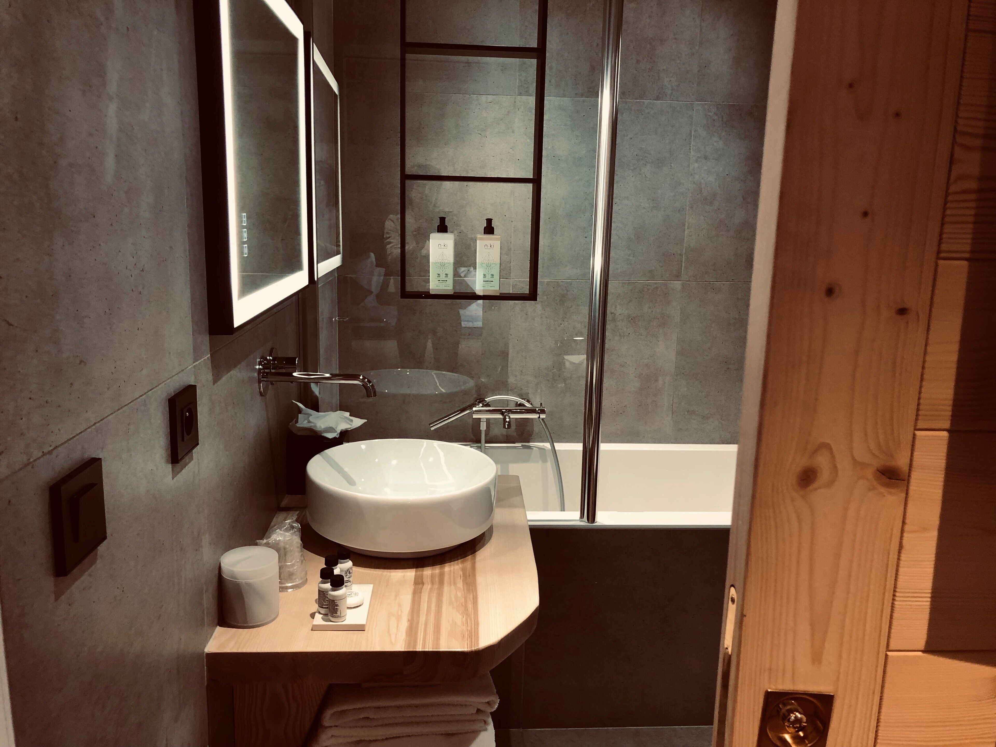 A modern bathroom with a round sink, a mirror, and a shower area.