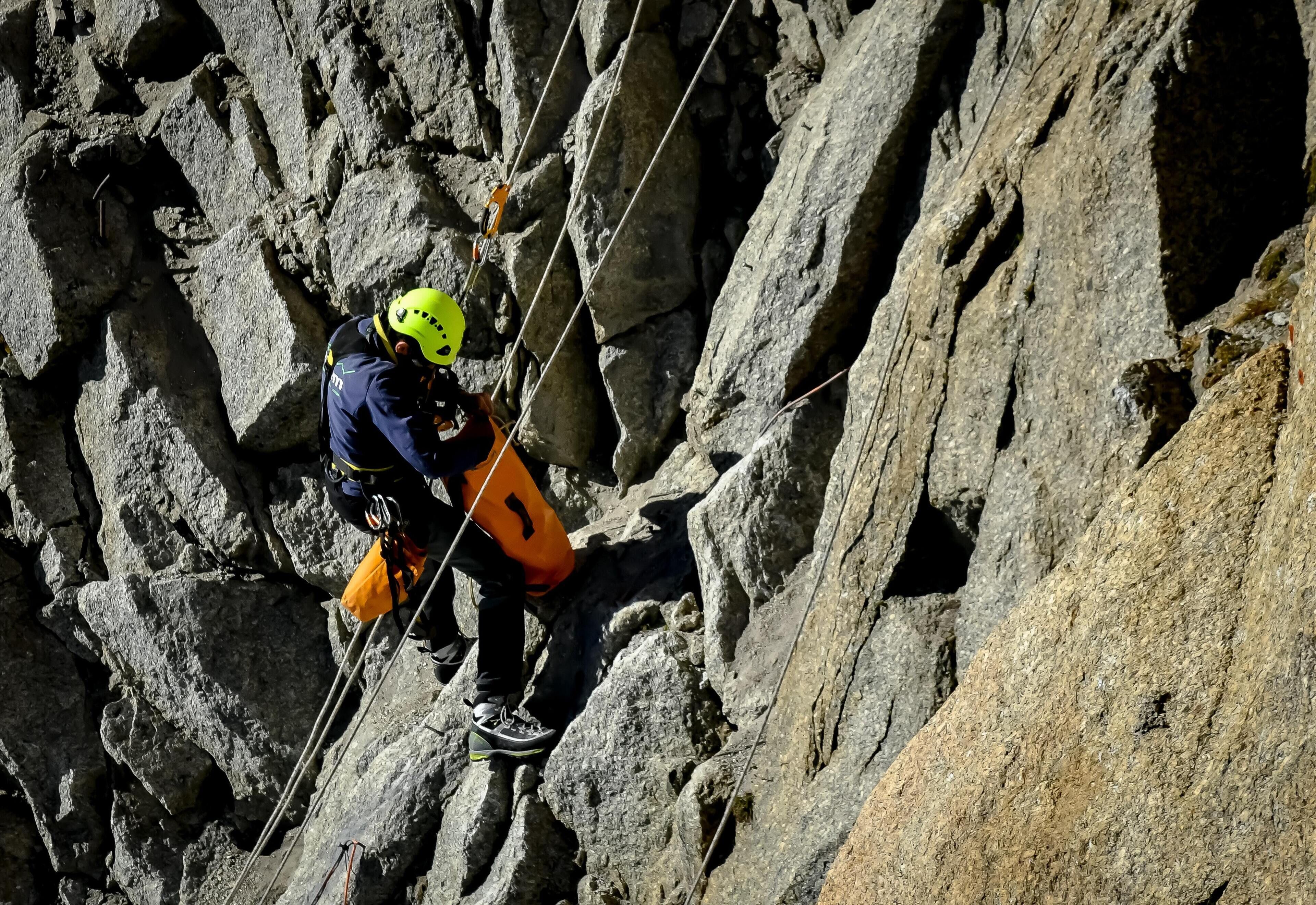 A person rappelling down a rocky cliff.