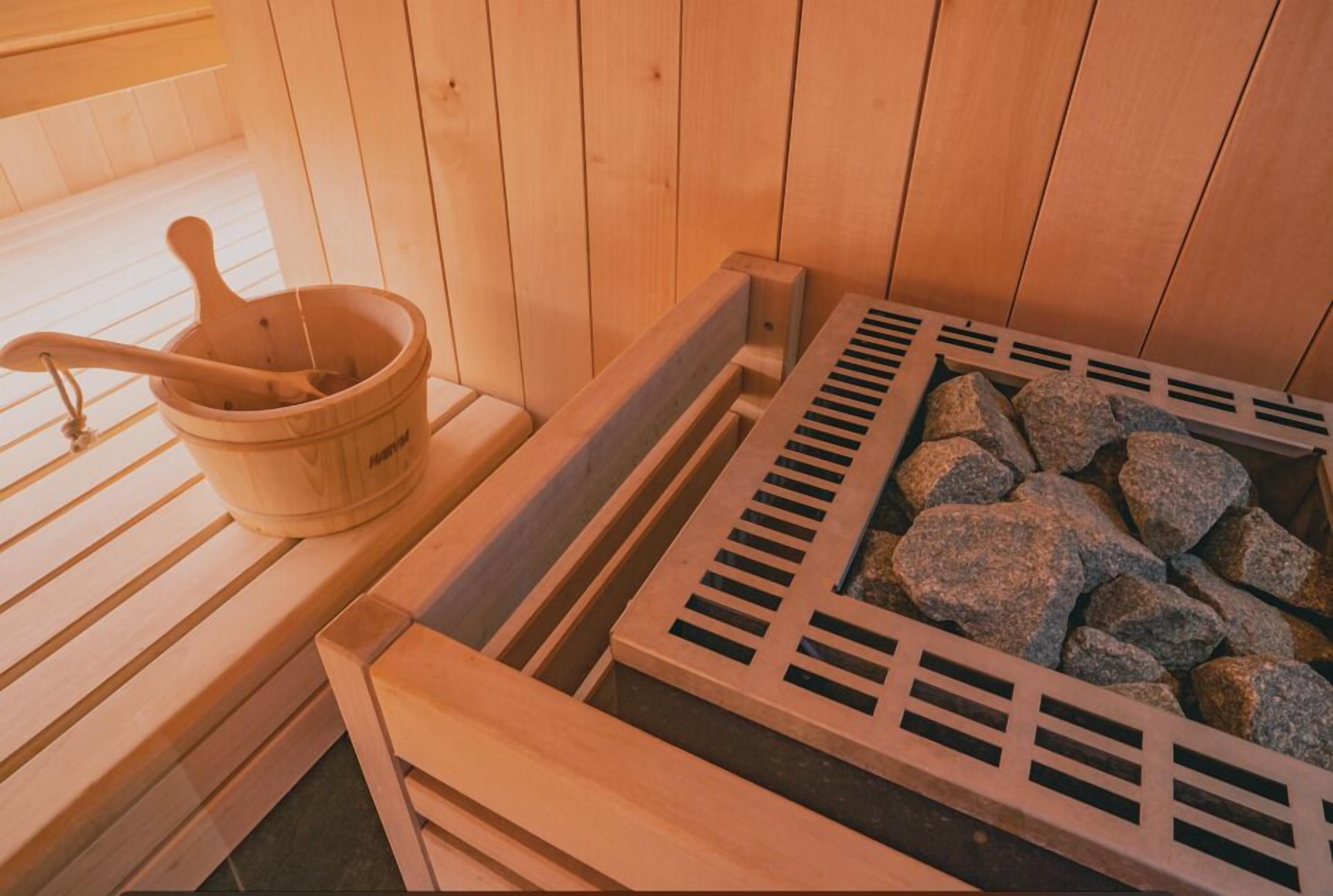 Uma sauna com bancos de madeira, um balde de madeira e uma bandeja com pedras.