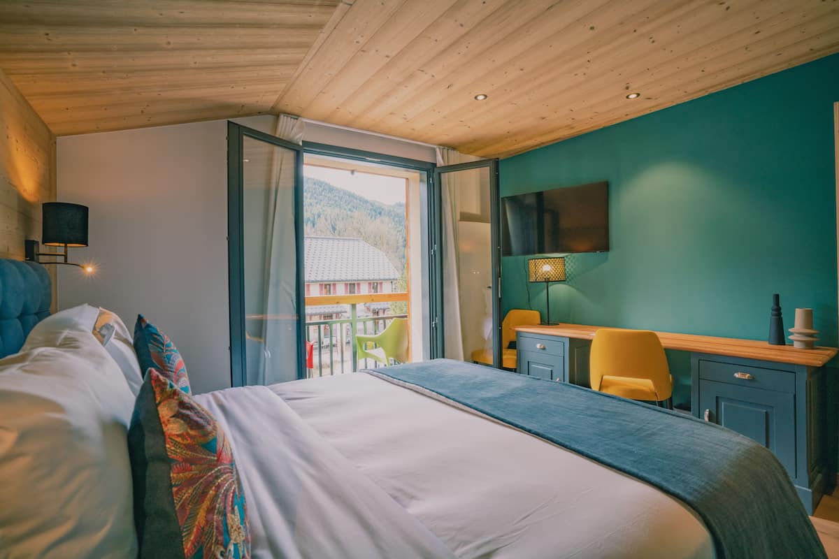 Ein Schlafzimmer mit einem Bett, einem Schreibtisch, einem Stuhl und einem Fernseher an der Wand.