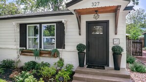 Uma casa com porta frontal escura, um pequeno alpendre e o número 327 na frente.