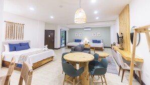 Een moderne hotelkamer met een groot bed, een slaapbank, een eettafel en een houten bureau.