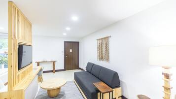 A modern living room with a sofa, TV, wooden furniture, and a door.