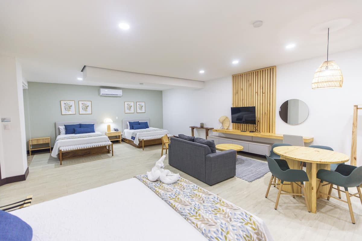 Une chambre d’hôtel moderne équipée de deux lits, d’un canapé, d’une table à manger et d’un téléviseur.