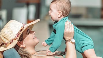 Una persona con sombrero de paja y camisa verde azulada, sosteniendo a un niño.