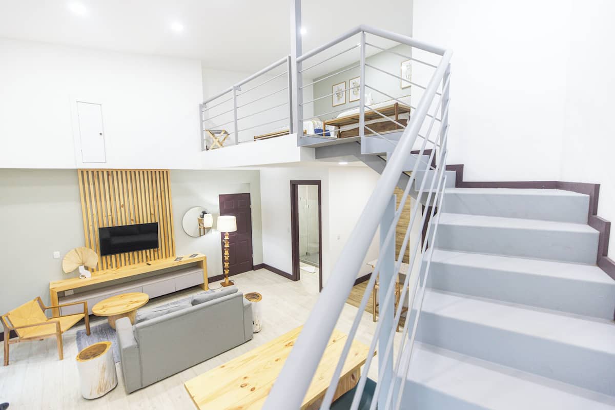 Un intérieur moderne comprenant un escalier, un canapé, un téléviseur et un coin repas.