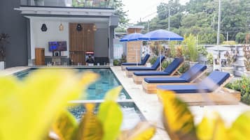 Una piscina al aire libre, sillones reclinables de piscina