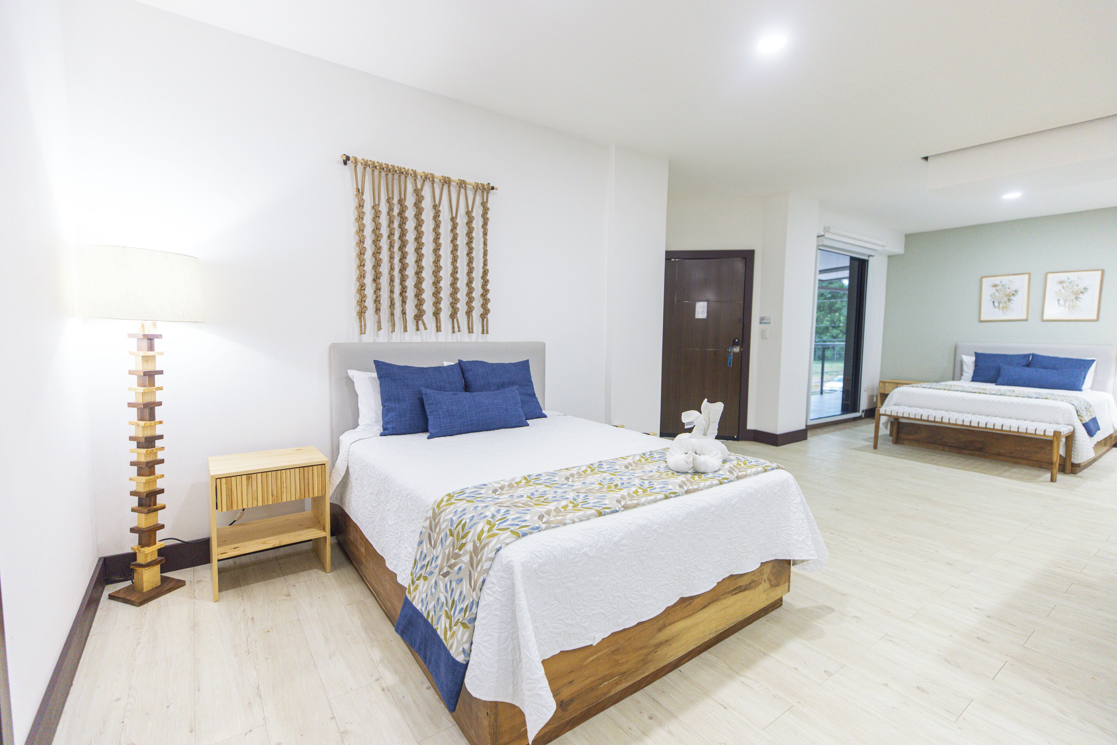 Un dormitorio con una cama grande, una mesita de noche, una lámpara y una puerta que da a un balcón.