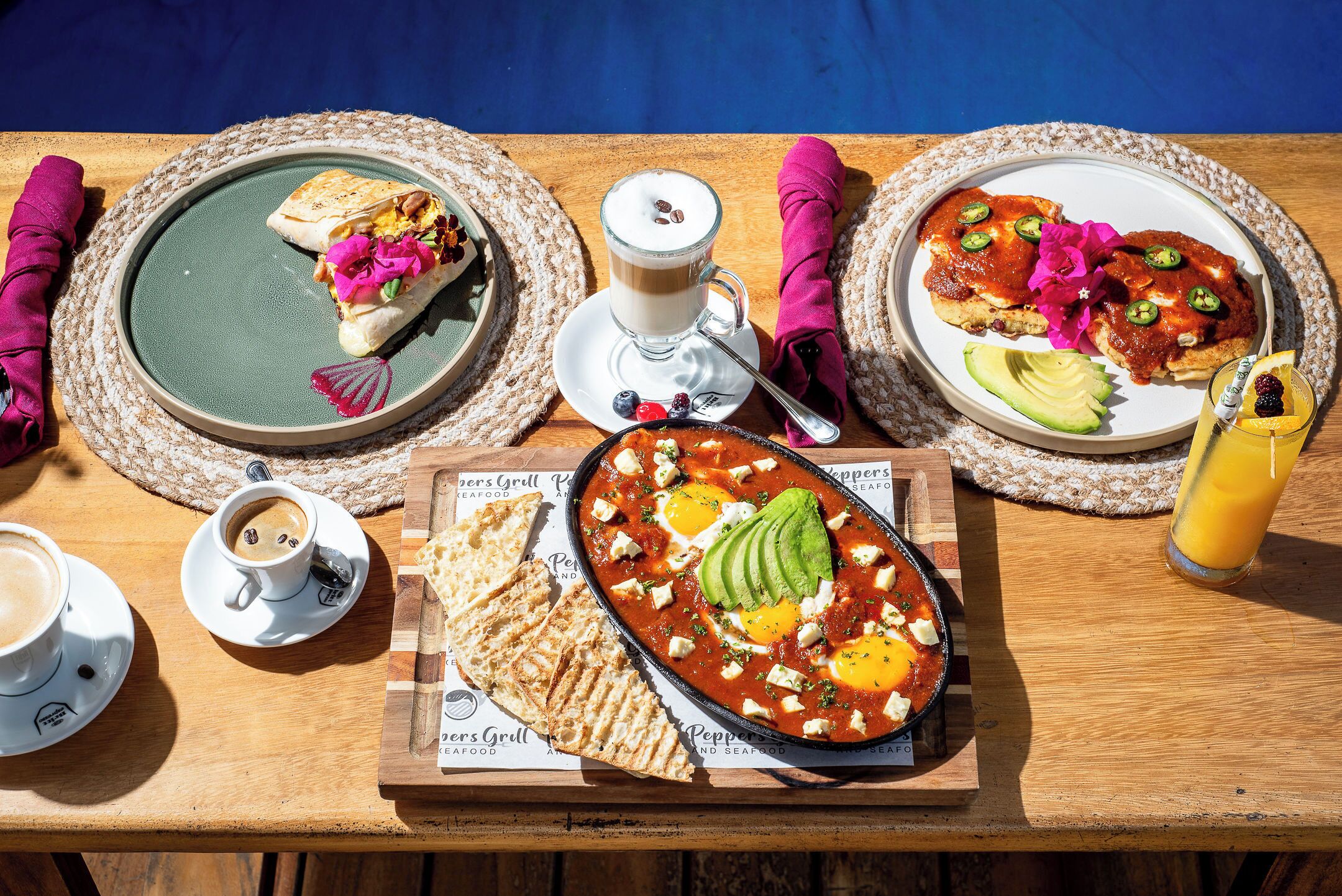 A breakfast table with plates of food, cups of coffee, and a glass of juice.
