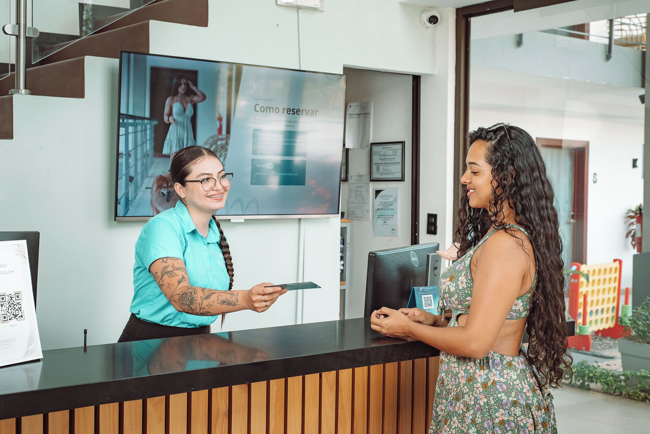 A reception desk with a wooden panel design, a digital screen displaying a photo of a woman in a dress, and a QR code on the counter.