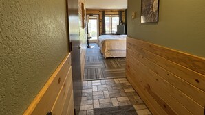 A narrow hallway with wooden walls and a tiled floor leading to a bedroom with a bed and a window. - Relax, Adventure, Views, Amenities +Memories (King) (Granby)