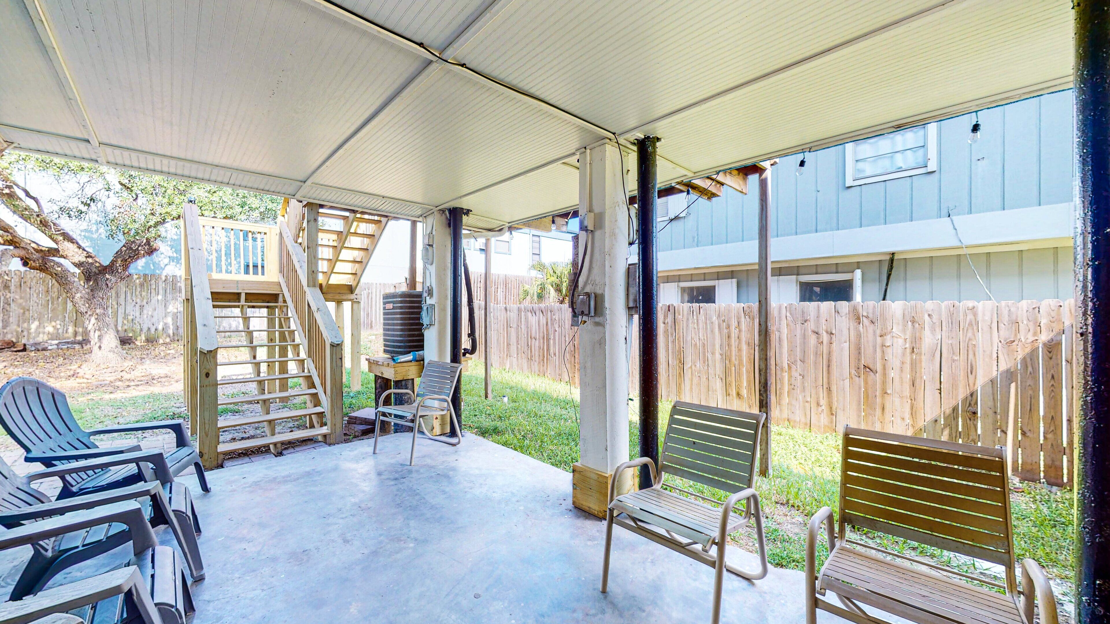 Un patio couvert avec des sièges d’extérieur, une terrasse en bois et une vue sur un immeuble résidentiel en arrière-plan.