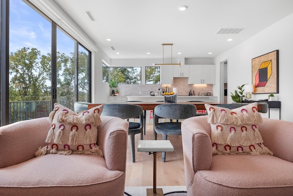 A modern living room with two plush chairs, a small table, and a kitchen in the background.