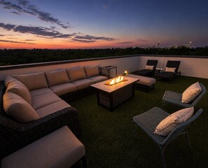 An outdoor seating area with a fire feature, lounge chairs, and a sofa.