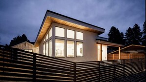 A modern house with large windows and a sloped roof, surrounded by a wooden fence. - Base Camp for Bend Explorers (Bend)