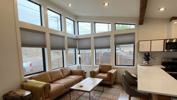 A modern living room with a brown leather sofa, a coffee table, and a patterned rug. - Base Camp for Bend Explorers (Bend)