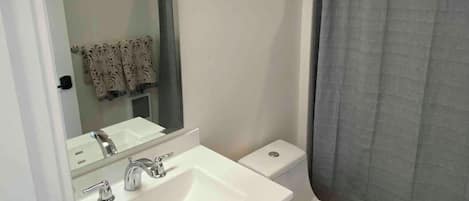 A bathroom with a white sink, mirror, and toilet.