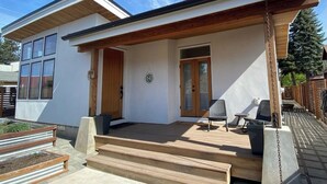 A modern house with a covered porch, a front door, and a small outdoor seating area. - Base Camp for Bend Explorers (Bend)