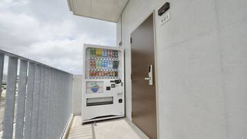 A vending machine with a variety of drinks and snacks, located next to a door with a number plate.