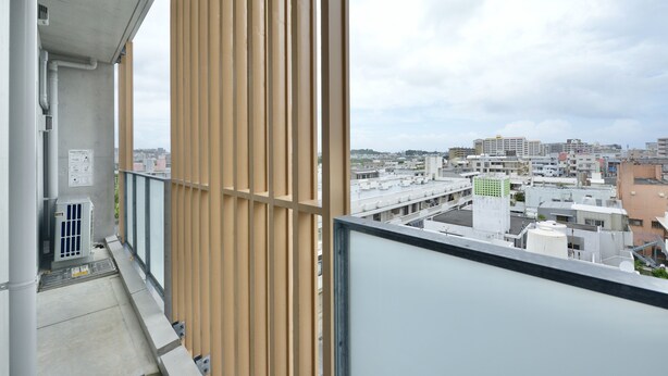 Ein Balkon mit Blick auf eine Stadtlandschaft, mit Gebäuden und einem bewölkten Himmel.