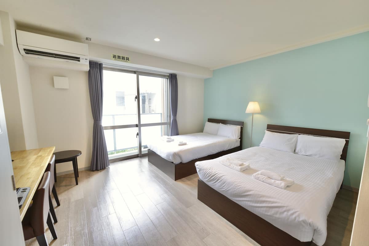 A hotel room with two beds, a desk, and a window with curtains.