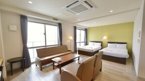 Ein Hotelzimmer mit einer Schlafcouch, einem Bett, einem Schreibtisch und einer Lampe.