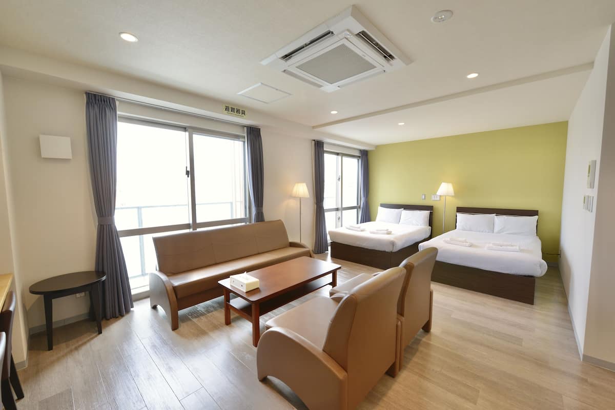 A hotel room with a sofa, a bed, a desk, and a lamp.