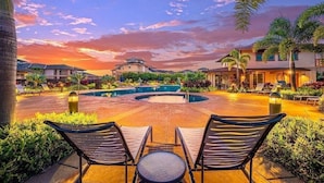A resort pool area with lounge chairs and a sunset view.