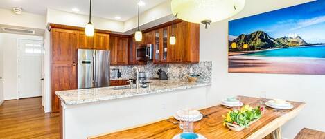 A modern kitchen with wooden cabinets, stainless steel appliances, and a marble countertop.