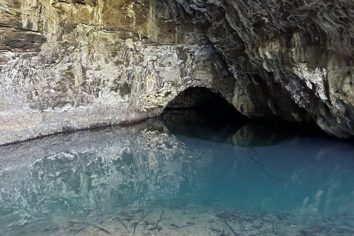 A cave with clear water and rocky walls.