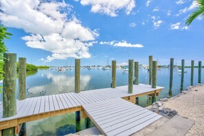 A wooden dock extending into calm water with boats docked in the background.