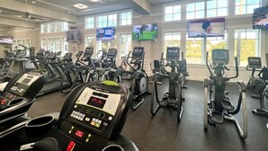 Une salle de sport équipée de plusieurs tapis de course, de vélos d’appartement et d’un appareil d’aviron.