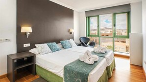 Une chambre d’hôtel avec deux lits, une table de chevet, une chaise et une grande fenêtre donnant sur un beau paysage.