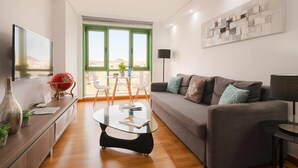 Un salon moderne comprenant un canapé, une table basse en verre, un téléviseur et un coin repas avec une table et des chaises.