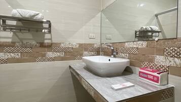 A modern bathroom with a large mirror, a white sink, and a towel rack.