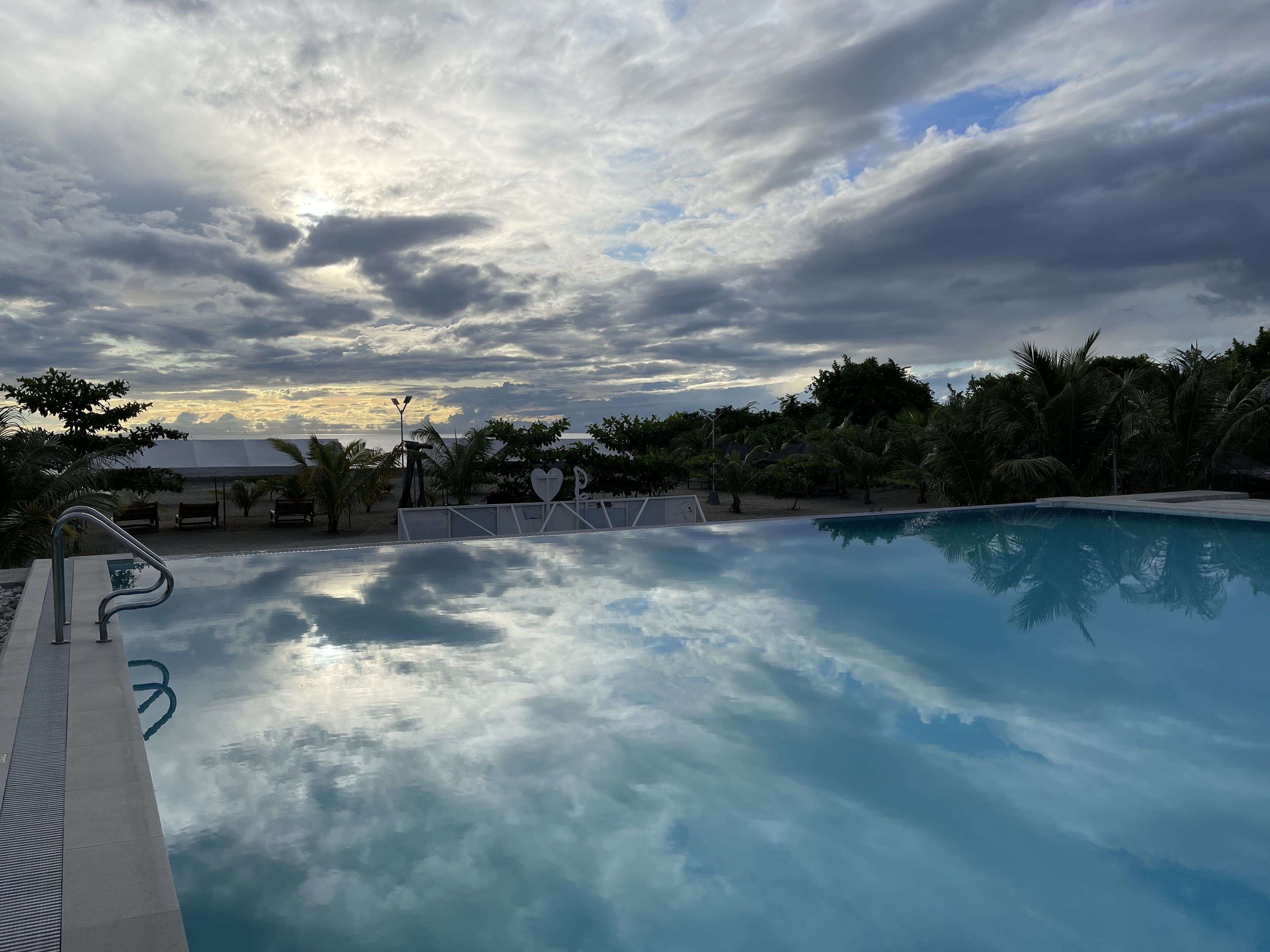 Une piscine avec vue sur le ciel et les palmiers.