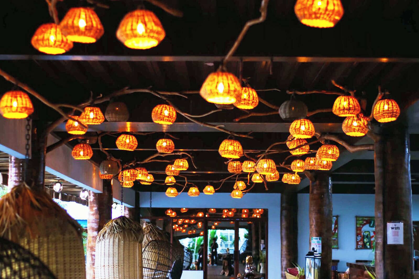 A restaurant interior with hanging lanterns, wooden beams, and a view of the street outside.