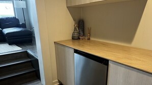 Ett kompakt kök med diskmaskin, en bänkskiva i trä och ett litet skåp.