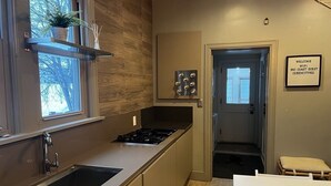 Ett modernt kök med en inbyggd spis, en diskho och ett fönster med en växt i. Det finns en dörr som leder till ett annat rum och en skylt som visar att det finns tillgång till Wi-Fi.