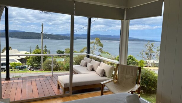 A bedroom with a large window overlooking a lake and mountains.