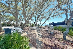 A patio area with picnic tables, a trash bin, and a view of the ocean.