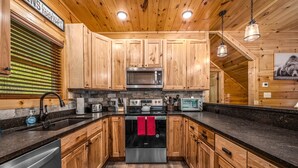Une cuisine moderne avec des meubles en bois, des appareils électroménagers en acier inoxydable et un plan de travail en granit.