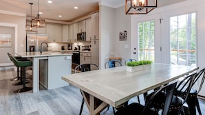 Een moderne keuken met een groot eiland, roestvrijstalen apparatuur en een landelijke kroonluchter.