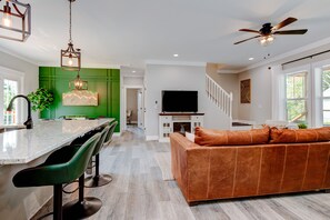 A modern kitchen with a central island, green accent walls, and a dining area with bar stools.