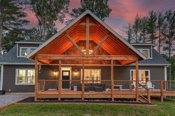 A two-story house with a wooden deck, a covered porch, and a large window overlooking the deck.