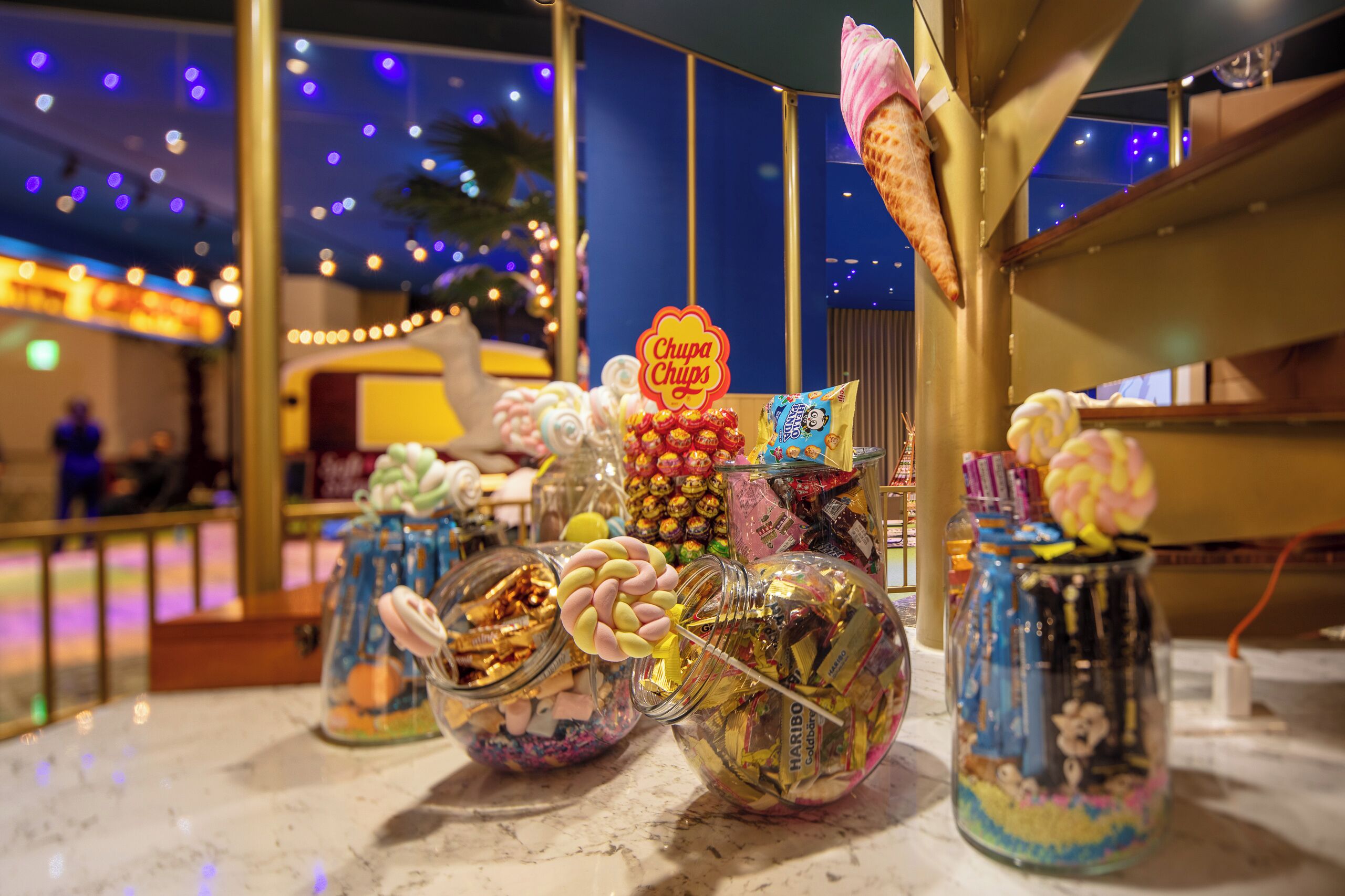 A display of various candies and chocolates in glass jars, with a 'Chupa Chups' sign visible.