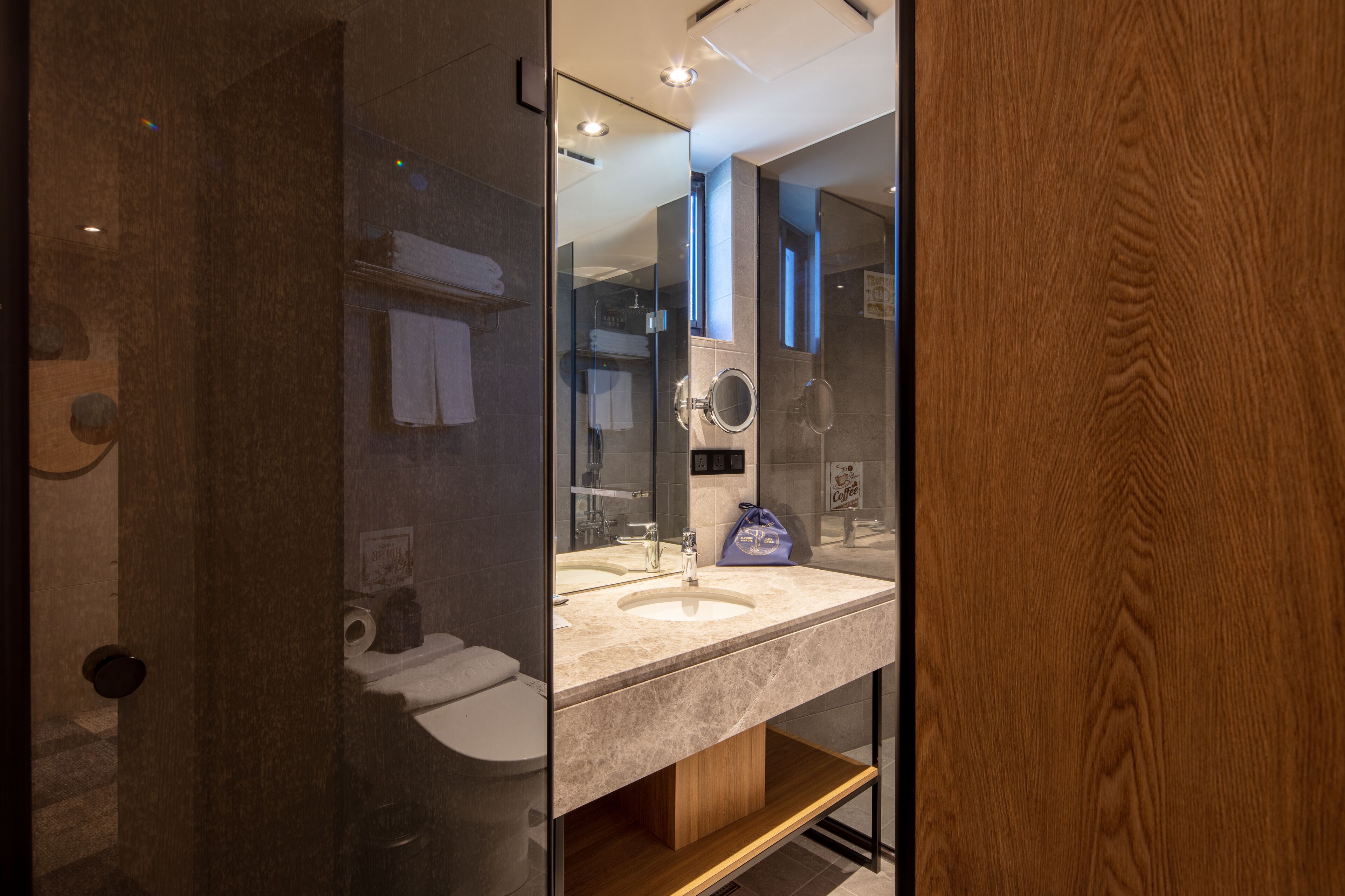 Un baño moderno con cabina de ducha de vidrio, tocador de madera y un espejo grande.