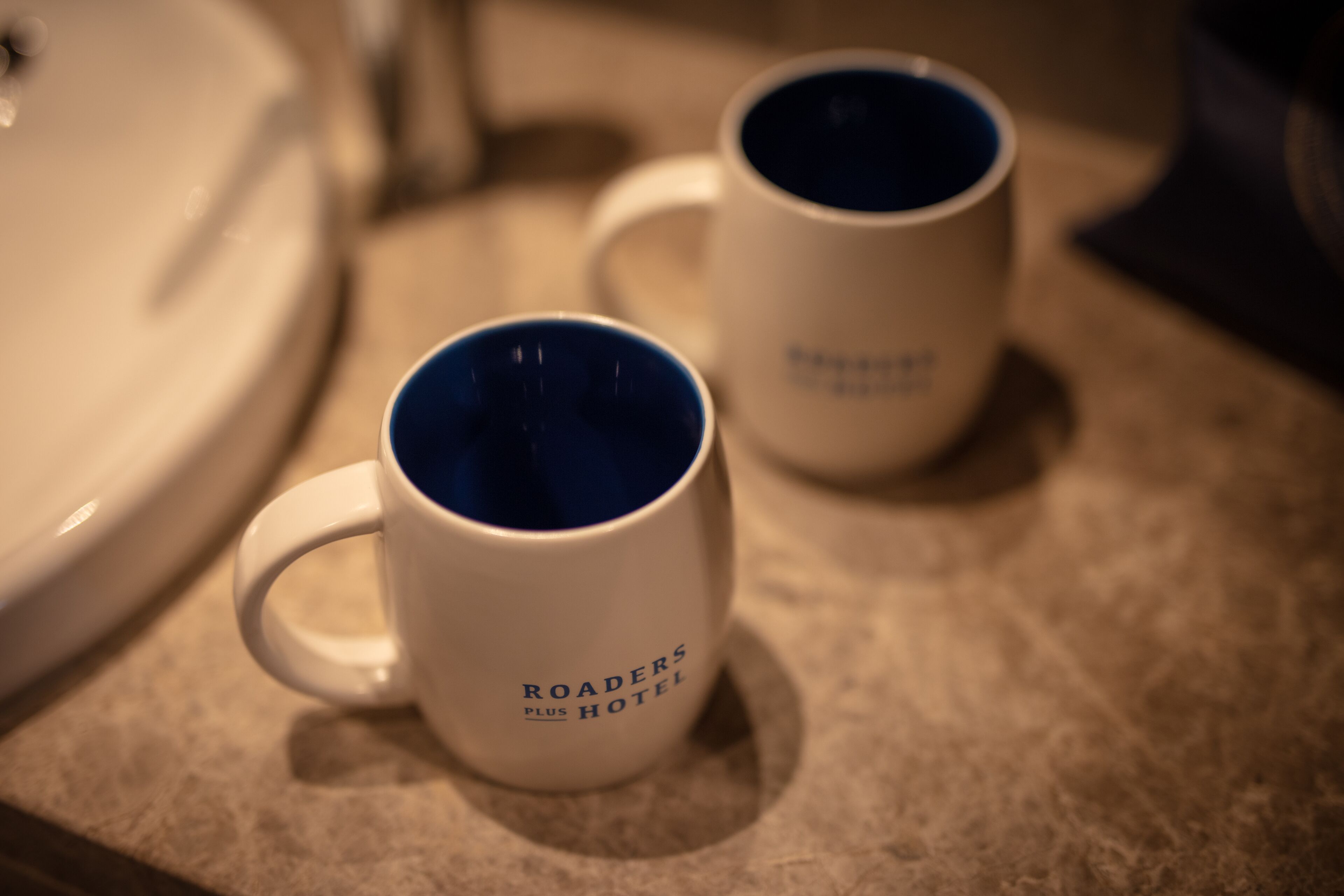 Dos tazas blancas con interior azul sobre una encimera.